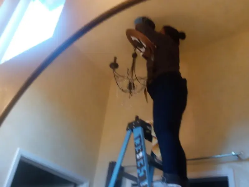 Electrician installing a chandelier in a Fox residence